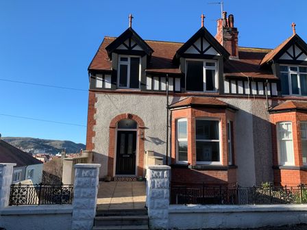 A semi detached house with bay windows and a front door with steps leading to it at 4 Tan Y Bryn Road in Llandudno