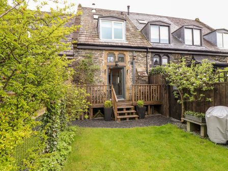A backyard with grass lawn wooden deck stairs and stone house at Two The Chapel Staveley