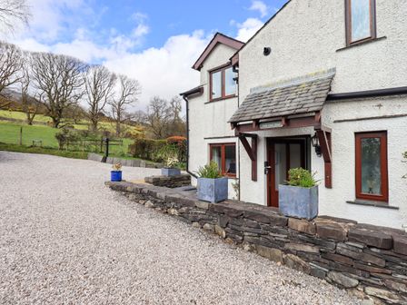 A house with a stone wall and gravel driveway at High Dow Crag in Coniston