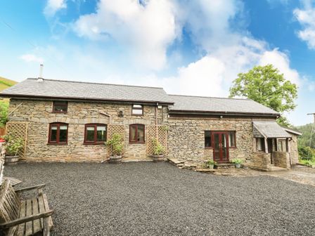 A stone house with multiple windows and a gravel driveway at Pant Y Rhedyn in Abbeycwmhir near Rhayader