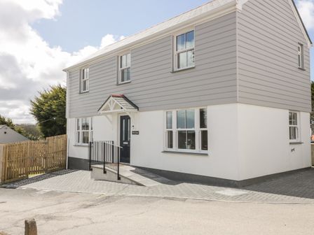 Exterior view of a two-story house with gray and white siding and a black front door at Gwel Nans in St Agnes