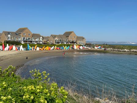 A beachfront with kayaks lined up near houses and water at Fairways in Wyke Regis