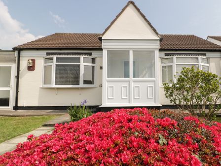 A front view of a single story house with a porch and flowers in the garden at Garden View in Quintrell Downs near Newquay