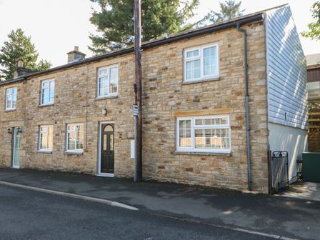 A stone house with multiple windows and two doors on a paved street at The Forge in Allendale