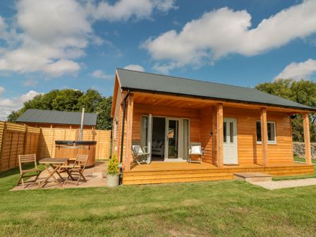 A wooden cabin with a porch and outdoor seating area with a small table and chairs at Peep o Day in Kirkbymoorside