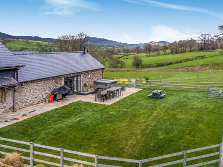 An outdoor area with a table and chairs at Y Beudy (The Dairy) Pedairffordd near Llanrhaeadr-Ym-Mochnant