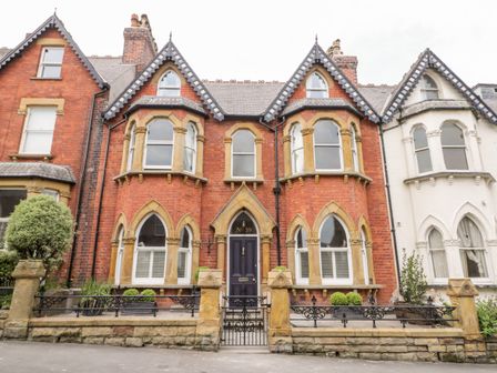 A red brick house with arched windows and a dark front door with stone pillars and wrought iron fencing at 39 West Street in Scarborough
