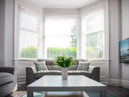 A living room with a white coffee table and a gray sofa with pillows at Oxford House in Llandudno
