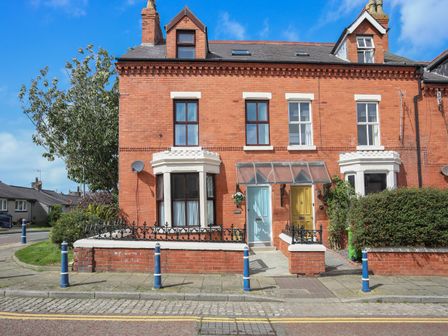 A red brick terraced house with blue and yellow doors and bay windows at Monfa in Cemaes Bay