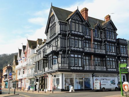 A street with multi-story black and white timber framed buildings and pastel-colored shops at 2 York House in Dartmouth