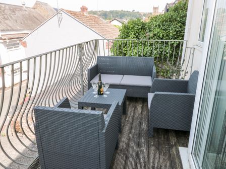 A balcony with outdoor seating furniture and a bottle with three glasses at Huffin Dartmouth