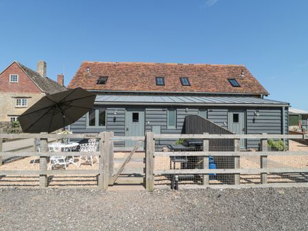 A fenced outdoor patio with a table umbrella and barbecue grill at Swallows 1 The Old Stables in Stanton Harcourt near Witney