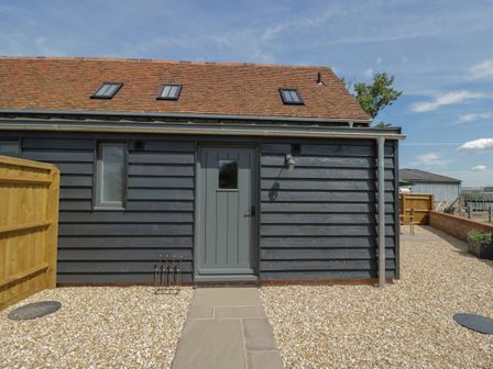 The exterior of a house with a wooden door and window under a roof with skylights surrounded by gravel Kingfisher 2 The Old Stables Witney