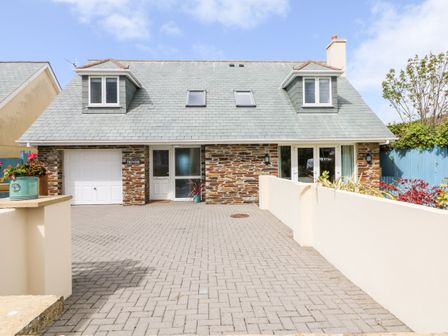 A driveway leading to a house with stone walls and a grey roof at Trevose House in Crantock