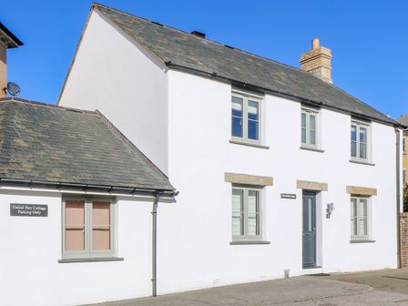 A white two-story house with grey windows and a slate roof at Fistral Bay Cottage in Newquay