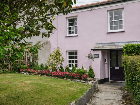The exterior of a pink cottage with a garden and pathway at Lantern Cottage in Charlestown