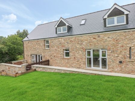A stone house with a slate roof and green lawn in front at Nuthatch Barn in Hensol near Pontyclun