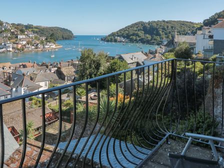 A balcony with a metal railing overlooking a coastal town and harbor with boats at 21 Above Town in Dartmouth