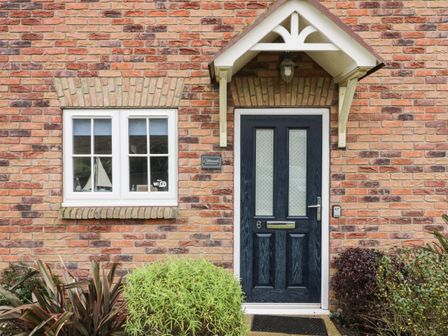 A brick house front with a black door number 6 and a white-framed window at Silversands in Filey