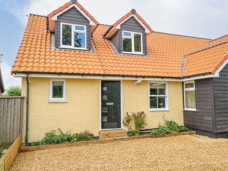 A front view of a house with yellow brick walls orange tiled roof black front door and gravel driveway at Walnut Shade in Old Buckenham