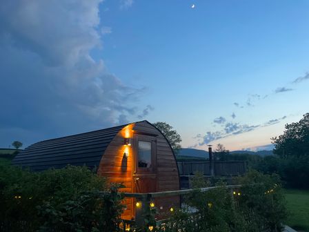 An outdoor cabin with lighting and trees at Embden Pod at Banwy Glamping Llanfair Caereinion