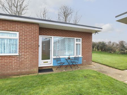 A small patio with a table and two chairs outside a brick house at 14 Siesta Mar in Mundesley