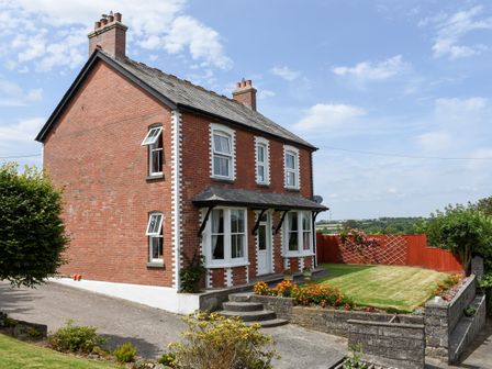 A brick house with a front lawn and flower beds at Silver Crooks Trewyn Nr Holsworthy