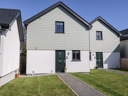 Front view of two attached houses with green doors and small front lawns at 4 Parc Delfryn Brynteg near Benllech