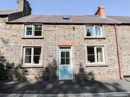 Stone cottage with a blue door and six windows at Oysterbank Cottage in Llangwm Pembrokeshire