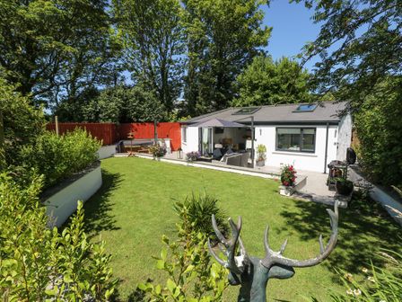 A garden with lawn shrubs and a patio area with outdoor furniture at Summerhouse in Penally