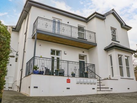A white two-story building with balconies and a paved driveway at Riviera Heights in Paignton