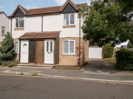 A semi detached house with a driveway and garage surrounded by trees and bushes at Littledown in Bournemouth
