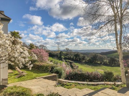 A garden with flowering trees and shrubs overlooking fields and hills at Wottonsbury in Ilsington