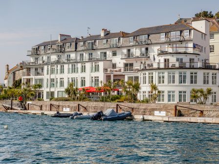 A waterfront building with balconies and boats docked in front at 32 The Salcombe in Salcombe