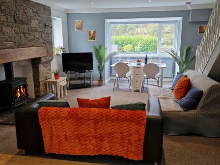 A living room with a fireplace, sofa and dining area at Bryn in Bethesda