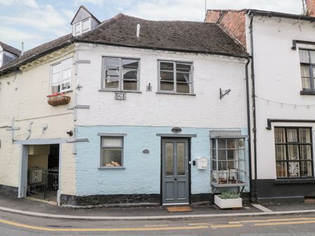 A two-story old building with a light blue and white exterior and a gray door at Cobblers Cottage in Upton Upon Severn