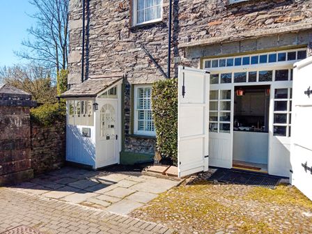 Stone house exterior with open white doors and paved entrance at The Old Carriage House in Clappersgate