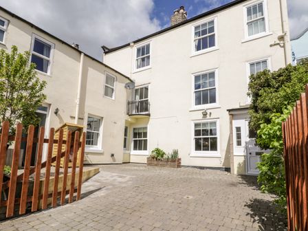 A paved courtyard with two-story cream buildings surrounding it and wooden fencing at Laurel House in Whitby