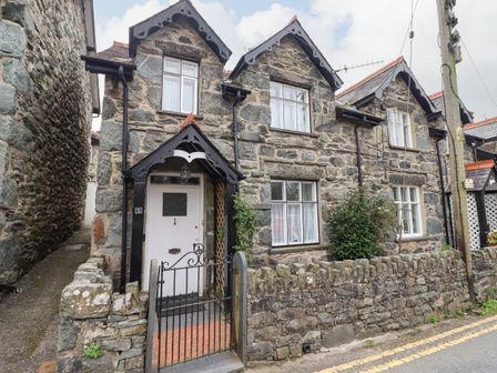 Stone exterior cottage with white door and black gate at Artro View in Llanbedr