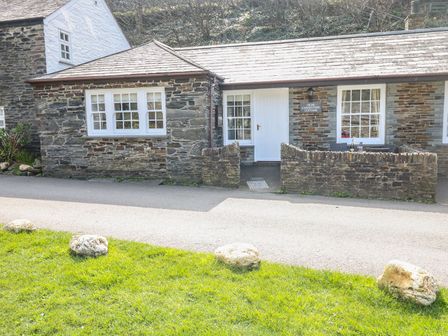 Stone cottage with a white door and windows and a small stone wall in front at Olde Carpenters Cottage Boscastle