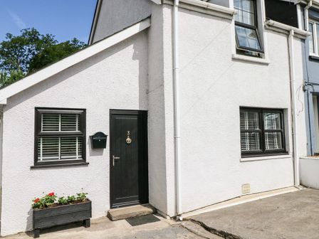 An exterior view of a building with white walls black door marked 3 and black-framed windows with flower box at 3 Bridge Villas in Narberth