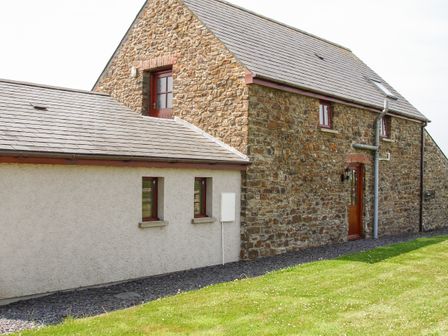 A stone and plaster house with a door and windows on a lawn at The Hagguard in Jeffreyston near Kilgetty