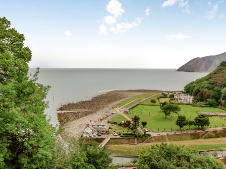 A coastal area with green fields buildings and a rocky shore at Clooneavin Apartment 4 in Lynmouth
