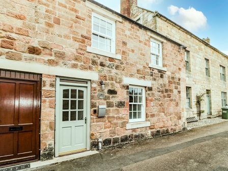 Stone exterior of a row of houses with multiple windows and doors at Curlew Cottage 2 Fenkle Street Holy Island