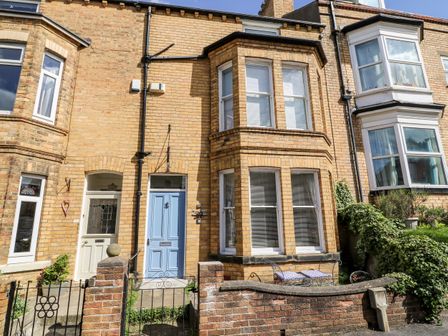 A brick terraced house with a blue door and bay windows at Seafarers in Scarborough
