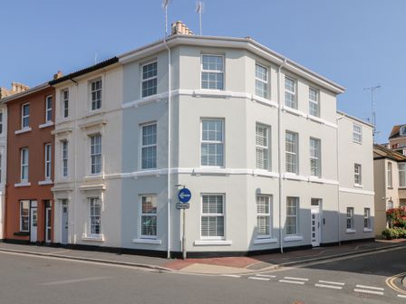 A street corner with white and brown buildings and windows with blinds at Sea Aster in Teignmouth