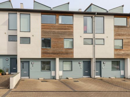 A row of modern townhouses with blue doors and parking spaces at 5 Quay Court in Newquay