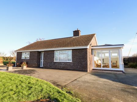 A single story brick house with a tiled roof and a sunroom with glass doors at Berwyn View in Trelydan near Welshpool
