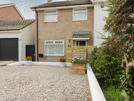 A front yard with gravel and potted plants outside a brick house with a wooden entrance at Estuary View in Newquay