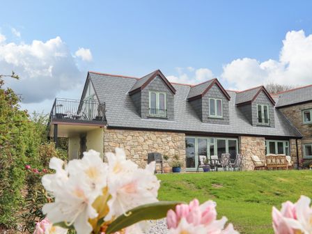 A stone house with dormer windows and outdoor seating on a lawn at Higher Kernick View in Helland near Blisland